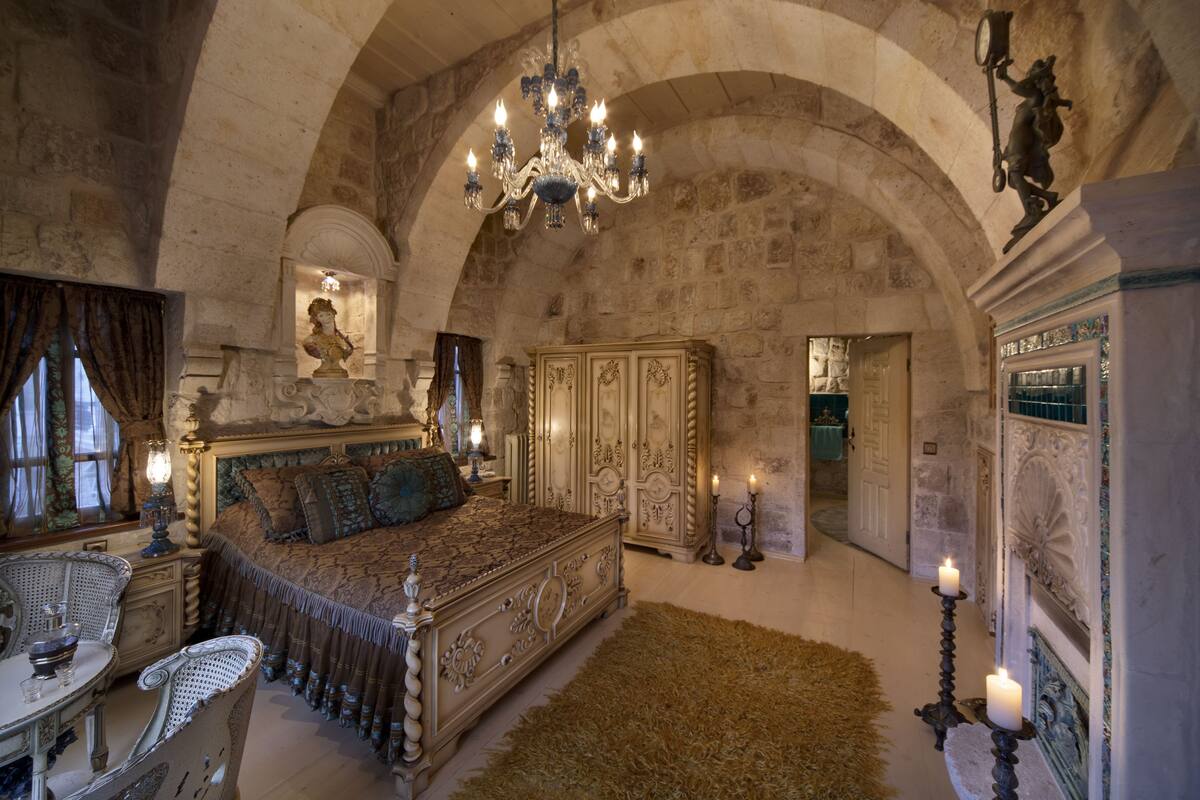 Une chambre à coucher luxueuse, dotée d’un grand lit, de meubles richement décorés et d’un lustre.