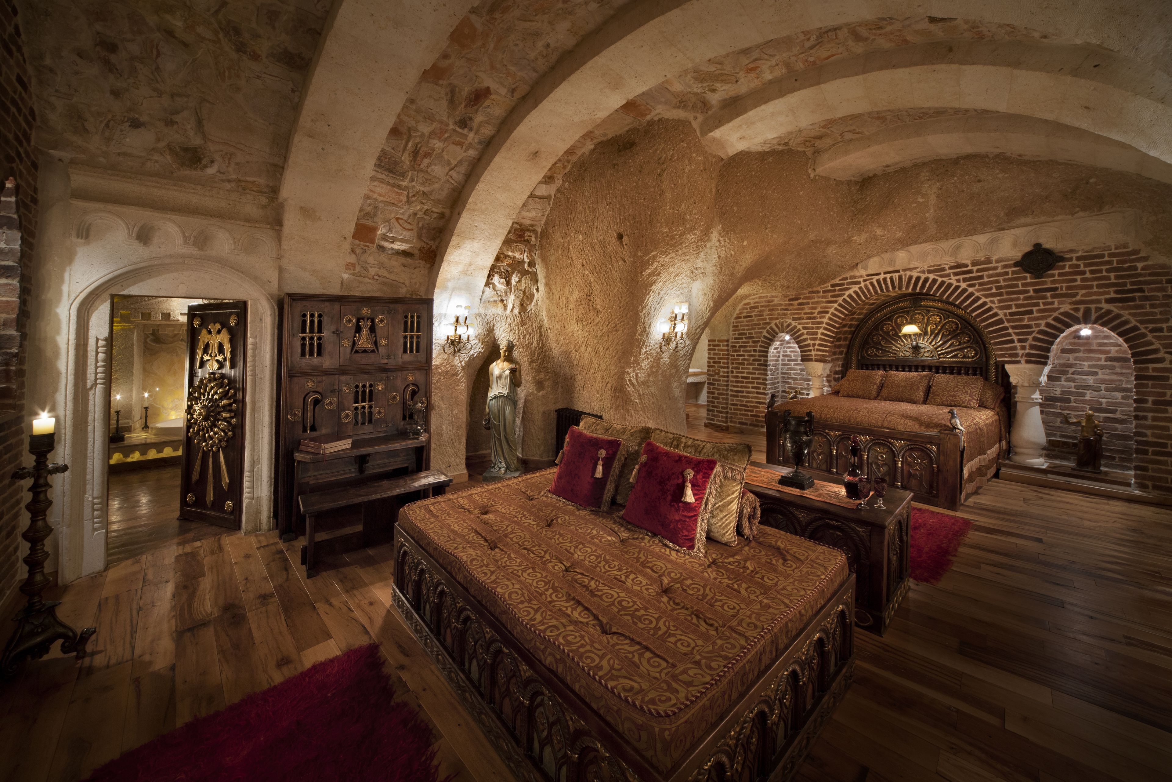 A room with a large bed, wooden furniture, and a stone wall.