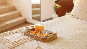 A neatly made bed with a tray of breakfast items including fruit, coffee, and juice. - Hotel Park Suites (Lima)