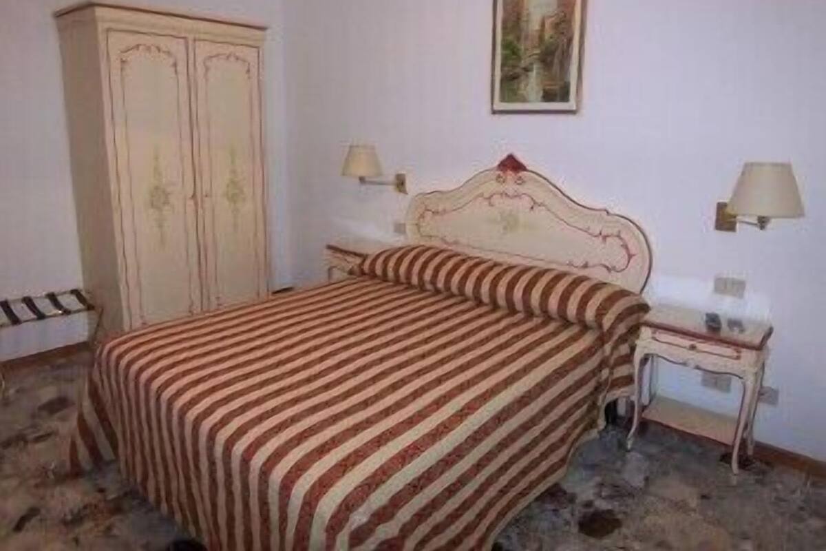 A bedroom with a bed, two bedside tables, a wardrobe, and a painting on the wall.