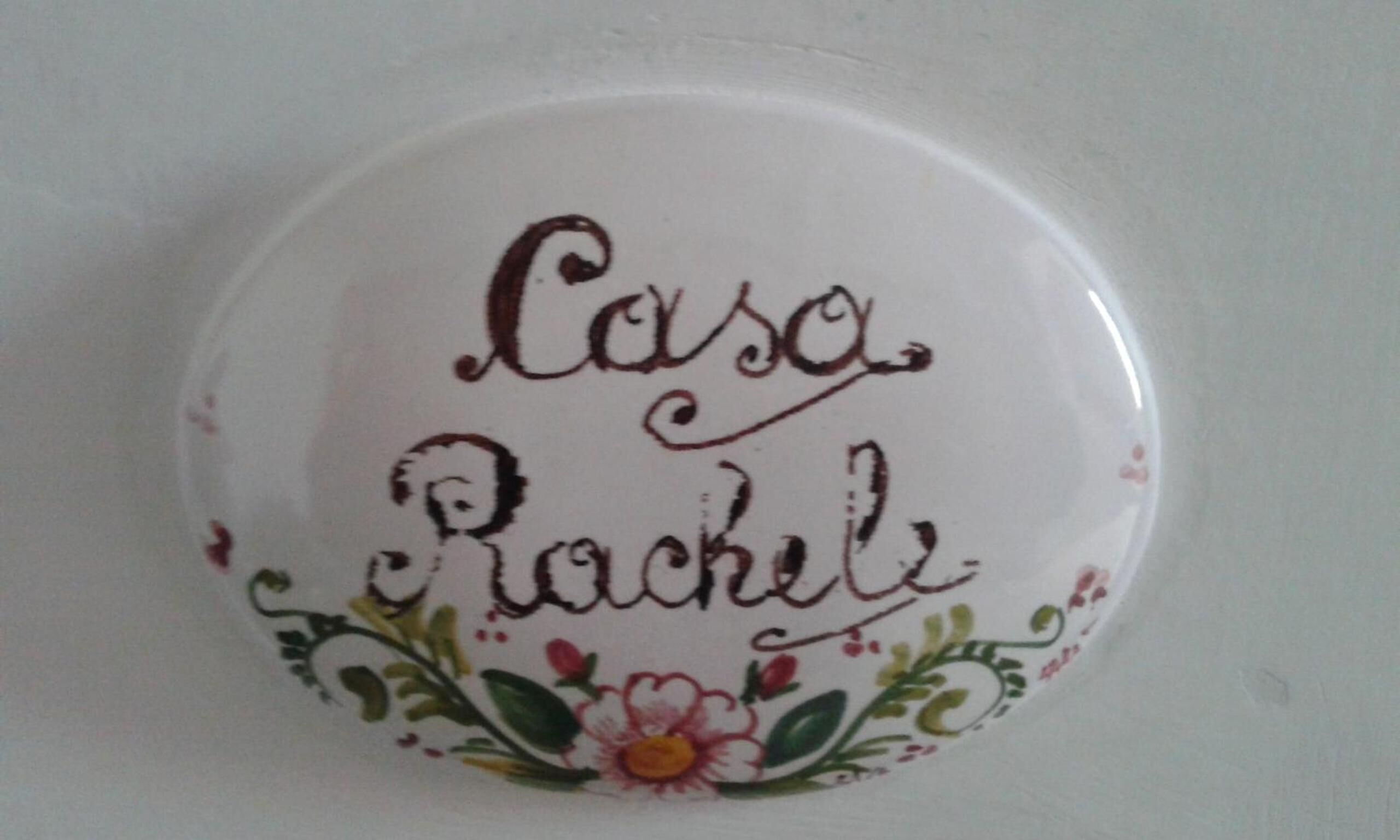 A white ceramic object with the name "Casa Rachel" and floral designs.