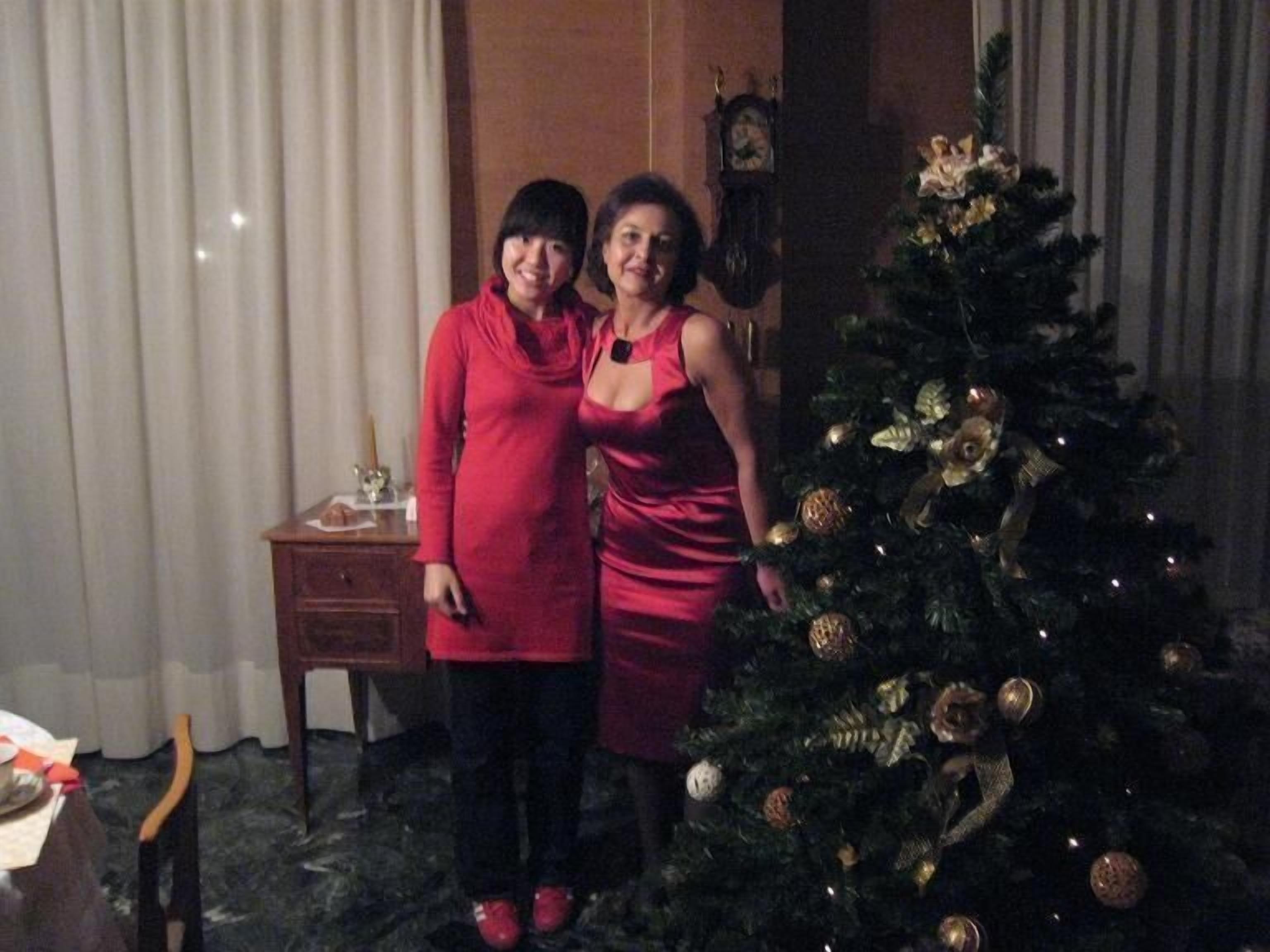 Zwei Personen stehen vor einem Weihnachtsbaum, der mit goldenen Verzierungen geschmückt ist.