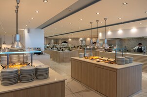 Una moderna disposición de bufé con múltiples estaciones de servicio, piso de baldosas de mármol e iluminación contemporánea.