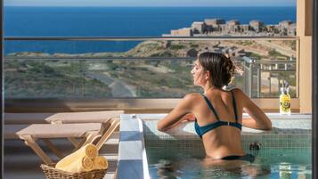 Una persona en una piscina con vistas al mar y edificios al fondo.