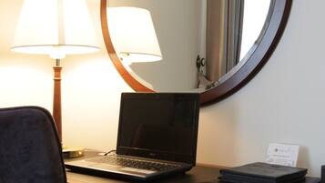 A laptop on a desk with a lamp and a mirror.