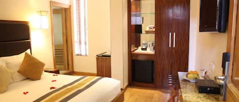 A hotel room with a bed, a desk, a mirror, and a wardrobe.
