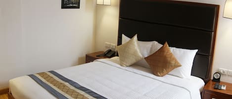 A neatly made bed with a patterned bedspread, a dark headboard, and two bedside lamps.