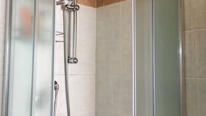 A glass-enclosed shower with a handheld showerhead and a fixed wall-mounted showerhead. - Perseo B&B (Rome)