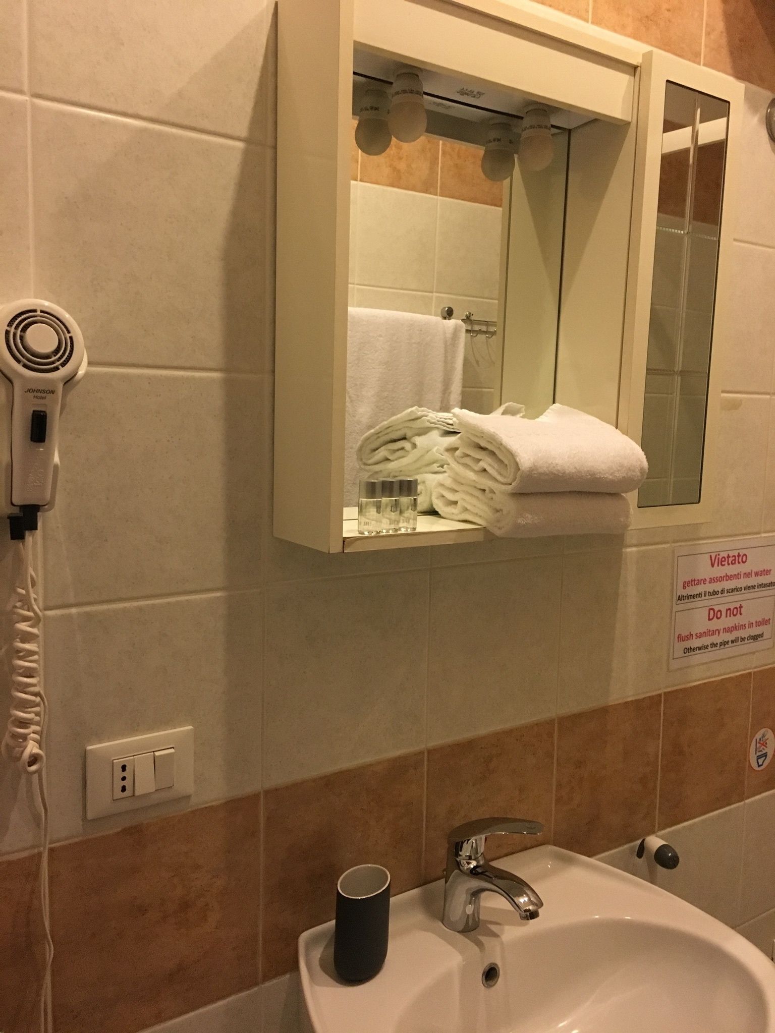 Un baño con lavamanos, espejo, toallero y secador de pelo.