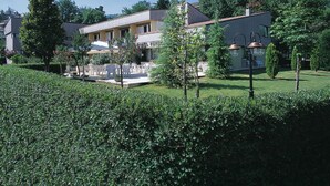A hotel with outdoor seating, a garden, and a clear blue sky. - Pennile (Ascoli Piceno)