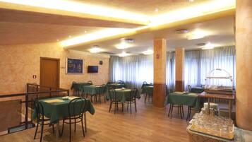 Un comedor con varias mesas y sillas, una estación de buffet y un reloj en la pared.