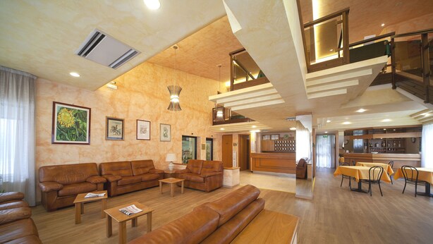 A spacious living area with a large sofa set, a dining table with chairs, and a staircase leading to an upper level. - Pennile (Ascoli Piceno)