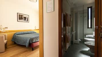 Un dormitorio con cama, una silla, una mesita de noche y un cuadro enmarcado en la pared.