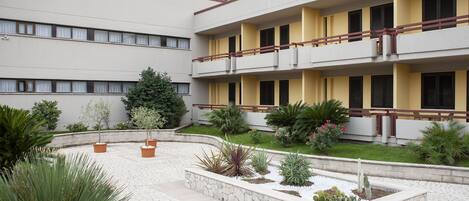 A courtyard with a multi-story building, potted plants, and a stone pathway.