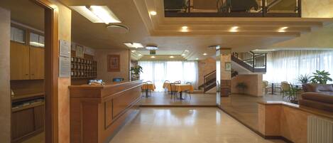 Un hall amplio con mostrador de recepción, una escalera y un comedor.