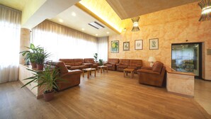 A spacious living room with leather sofas, wooden coffee tables, and potted plants. - Pennile (Ascoli Piceno)