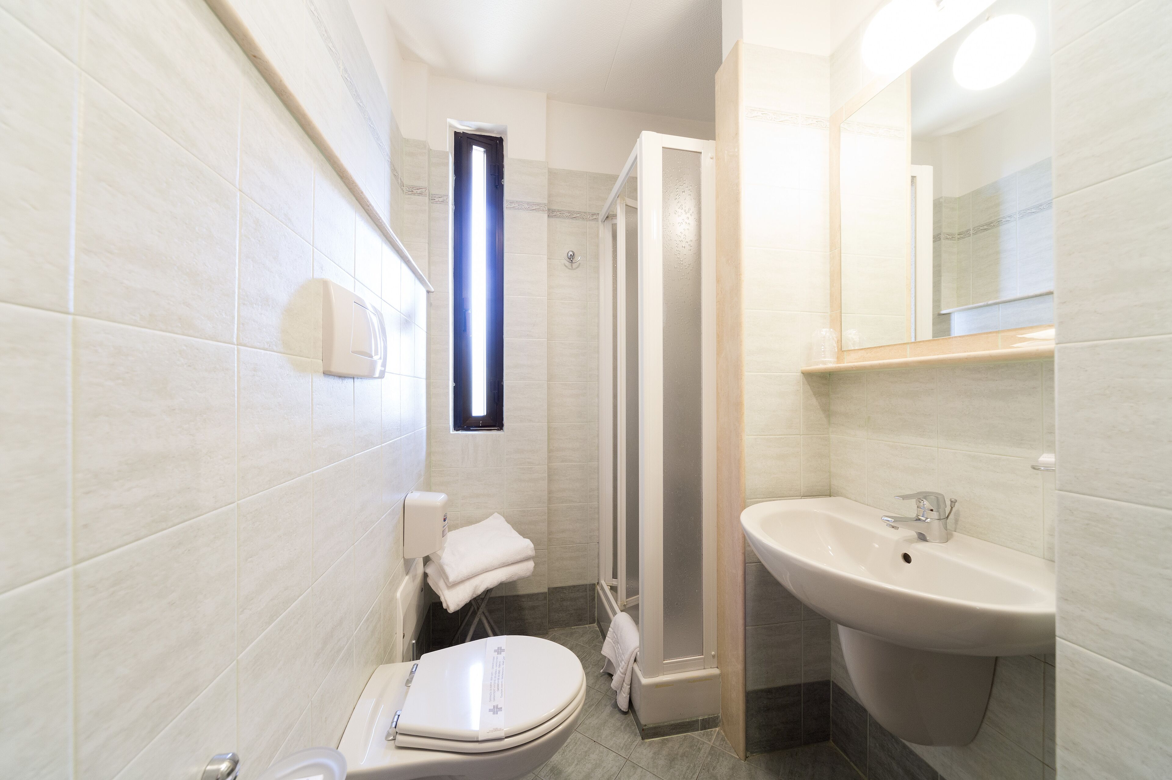 Un bagno moderno con toilette, lavandino e doccia.