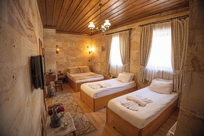 Habitación tradicional con dos camas de madera, una pared de piedra, techo de madera y un candelabro.