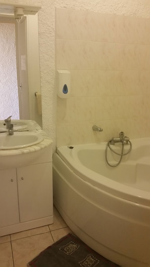 A bathroom with a sink, mirror, and bathtub. - Le Relais des Corbières (Lezignan-Corbieres)