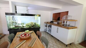 A dining area with a wooden table, chairs, and a large aquarium. - Hotel Villa Roseraie (Vence)
