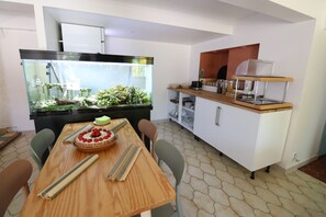A dining area with a wooden table, chairs, and a large aquarium. - Hotel Villa Roseraie (Vence)