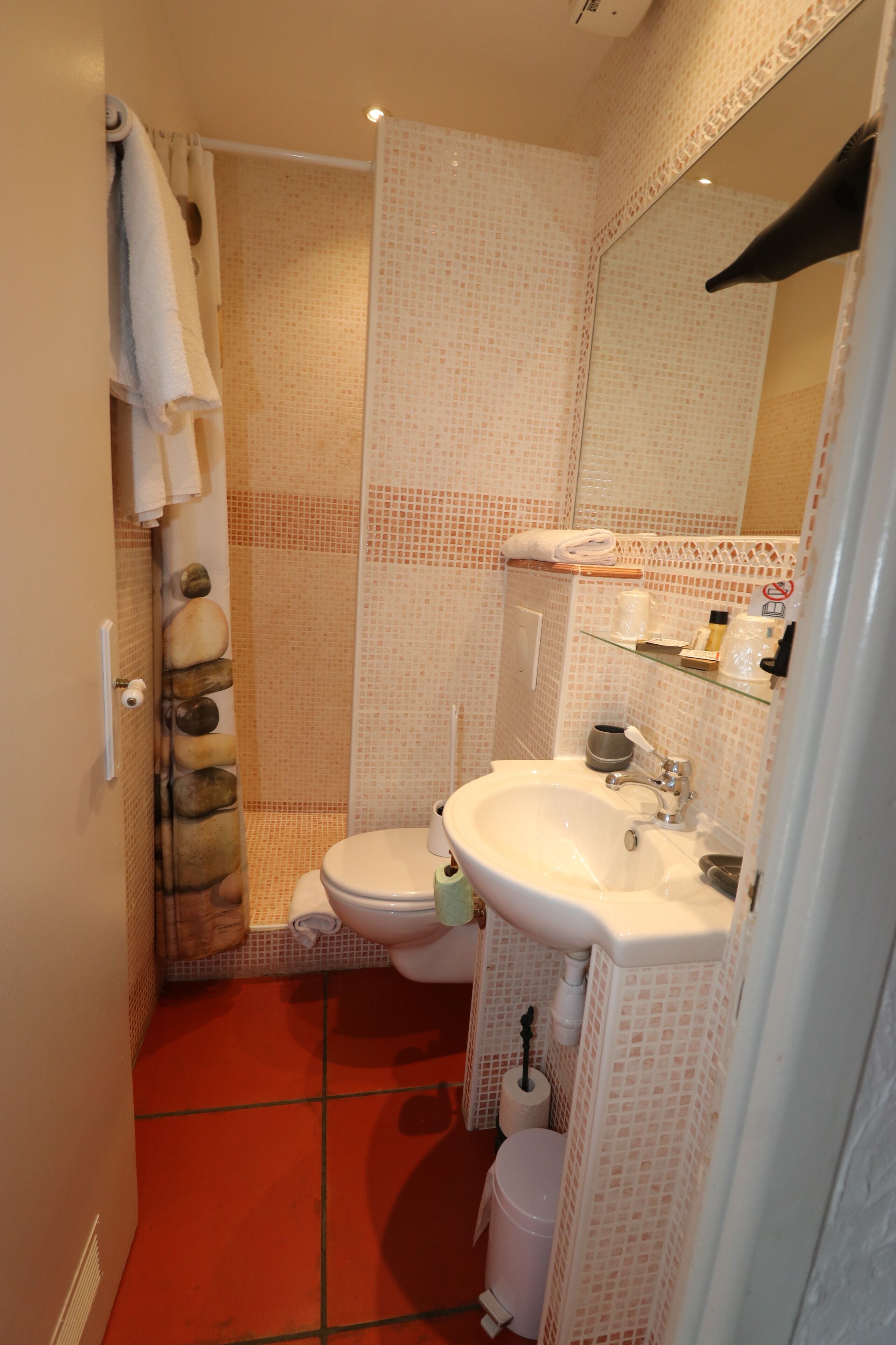 A small bathroom with a toilet, sink, and shower.