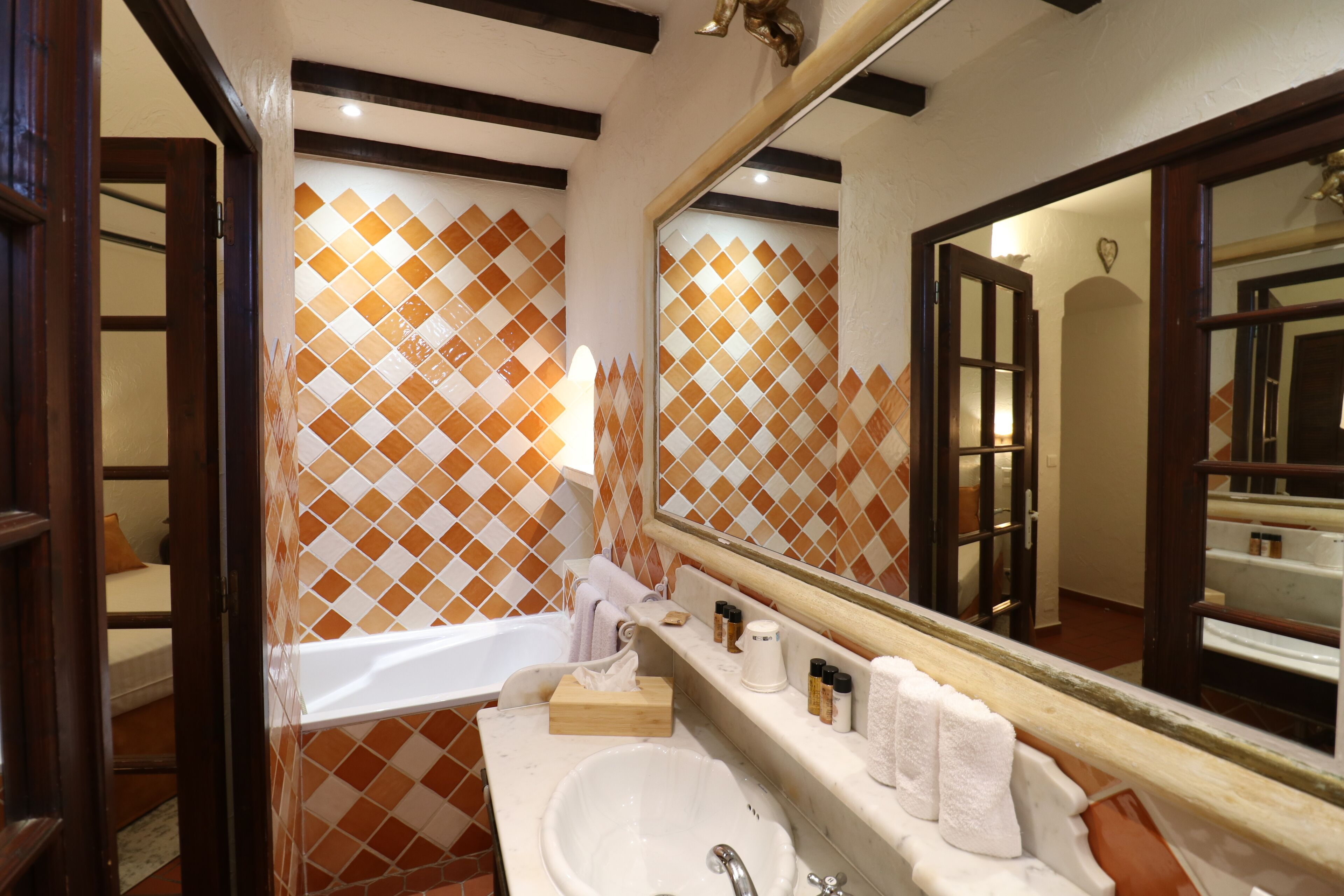 Un baño con lavamanos blanco, un espejo y un papel tapiz estampado.