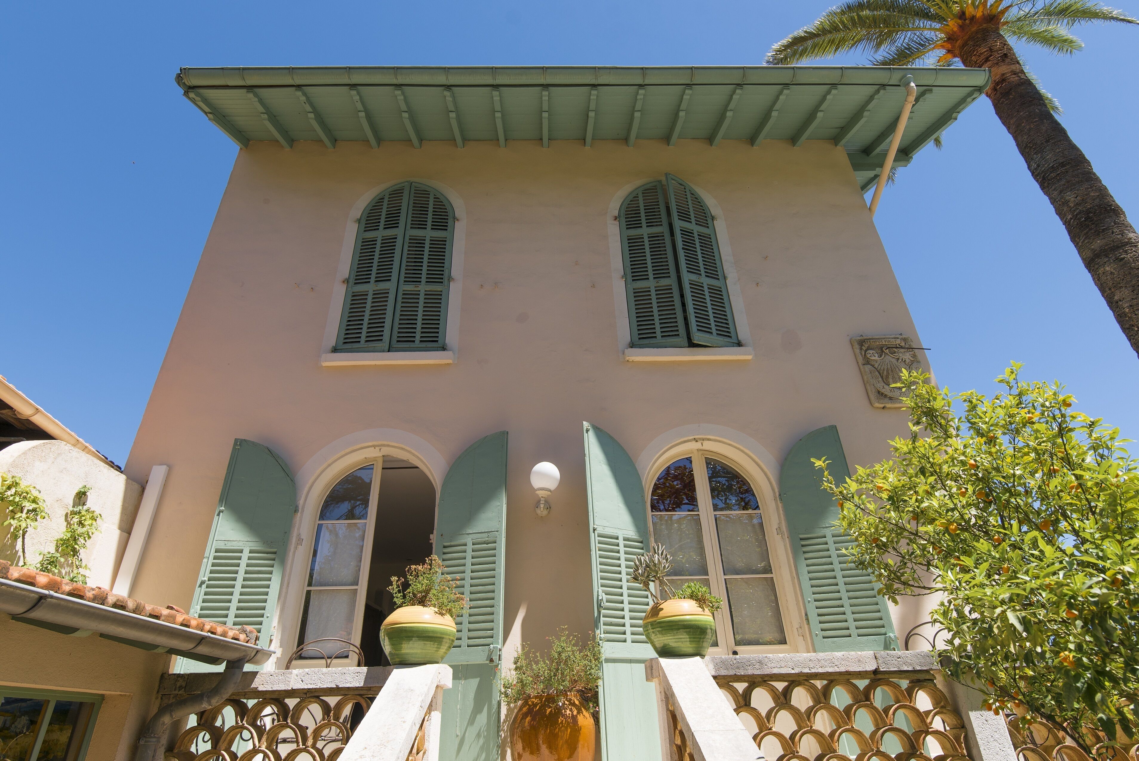 A two-story building with arched windows and green shutters.