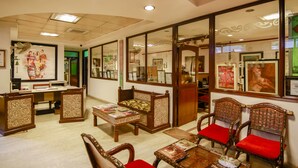 Um hall com mobiliário de madeira, um balcão de recepção e quadros nas paredes.