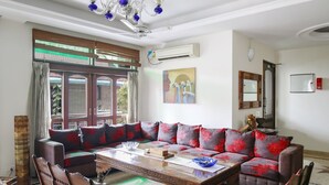 Uma sala de estar com sofá, cadeiras, mesa de centro de madeira e lustre.