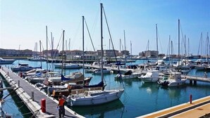 A marina with numerous boats docked, a pier, and buildings in the background. - La Papaya (Pisa)