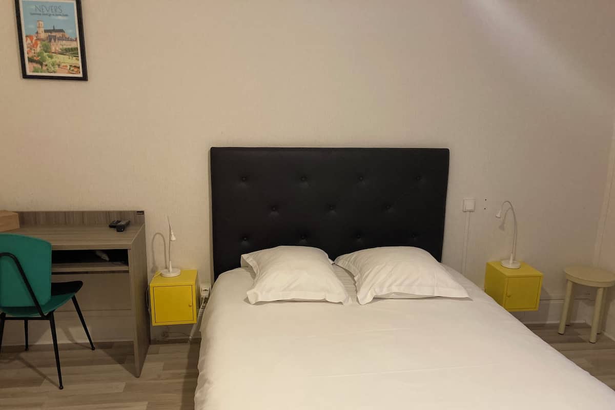 Quarto de hotel bem organizado, com cama, escrivaninha e cadeira.
