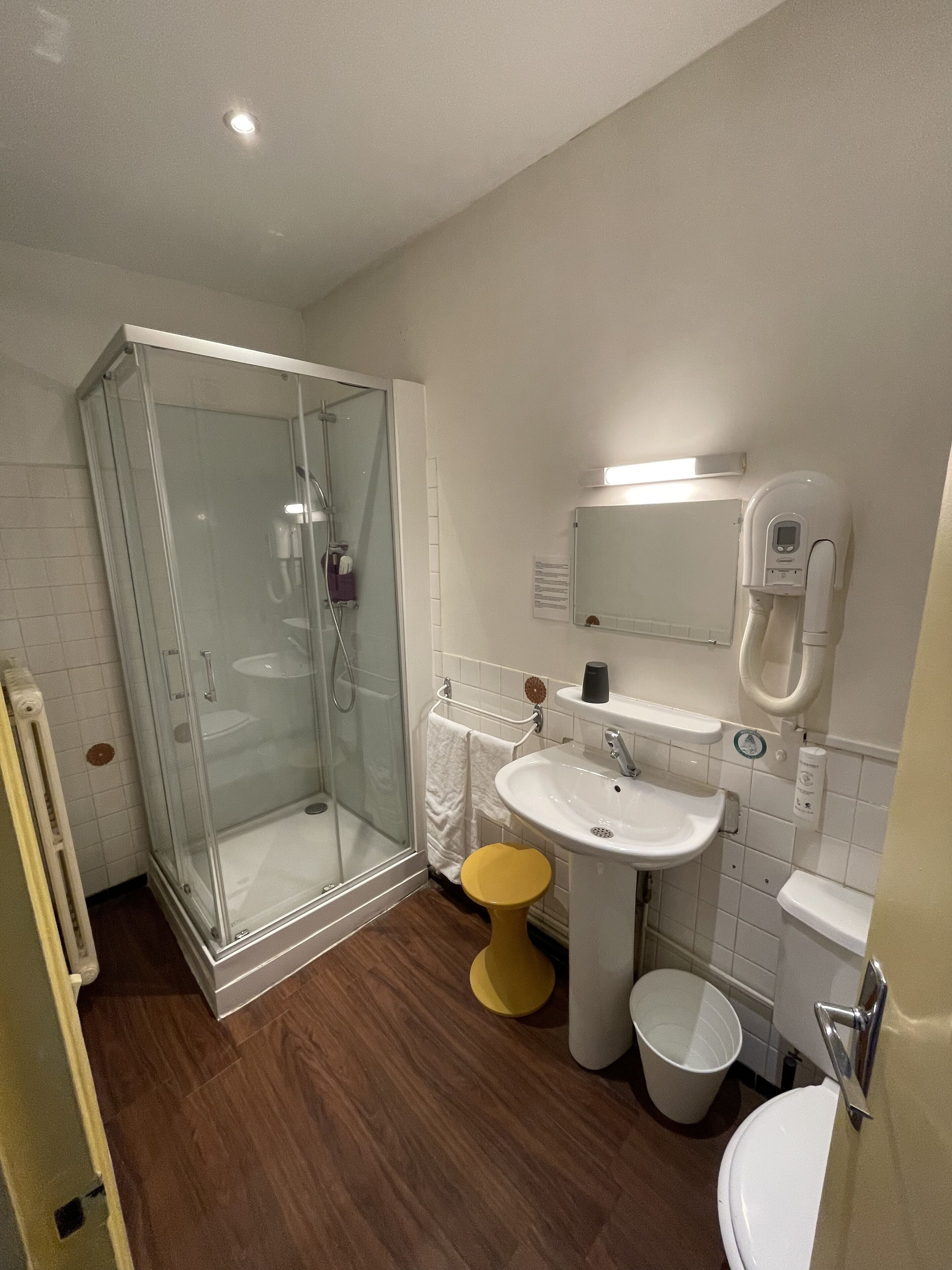 Une salle de bain moderne avec une douche à parois de verre, un lavabo sur colonne, des toilettes et un bidet.