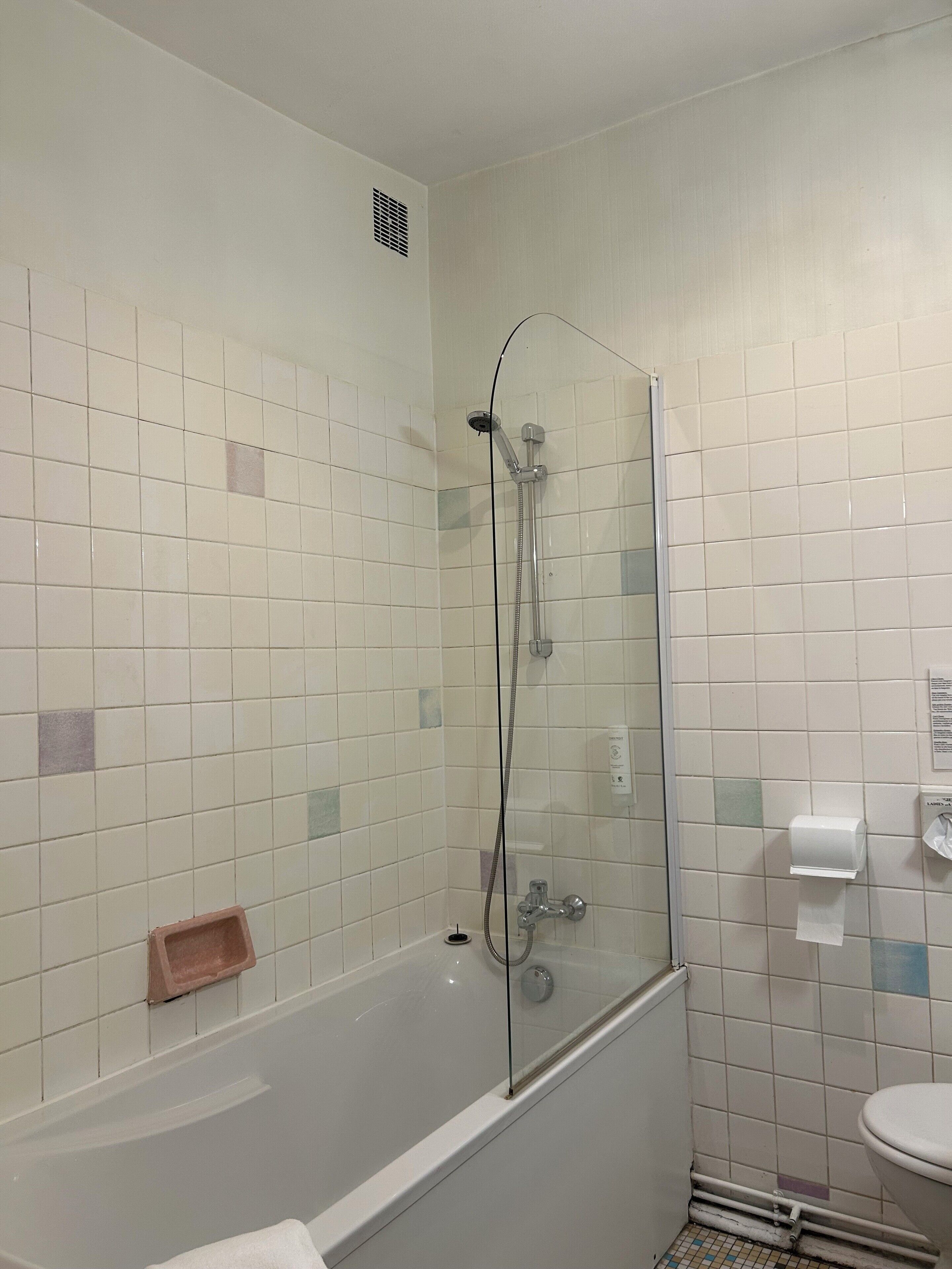 Un baño con ducha envuelta en vidrio, una bañera blanca y un inodoro.