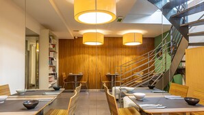 Un comedor moderno con paredes de madera, escalera de metal e iluminación colgante.