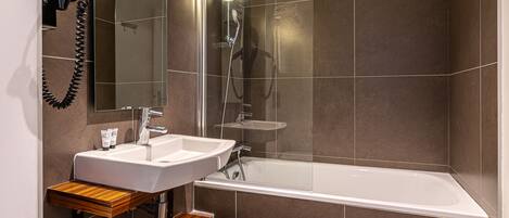 Un baño moderno con lavamanos blanco, tocador de madera y una bañera grande.