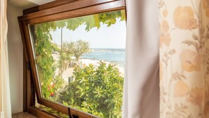 A window with a view of a beach, greenery, and a clear sky. - Hotel Costa Dorada (Dorgali)