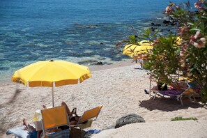 En la playa, sillas reclinables de playa, sombrillas, toallas de playa