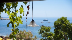 A hanging light fixture with a view of the sea and boats in the background. - Hotel Costa Dorada (Dorgali)