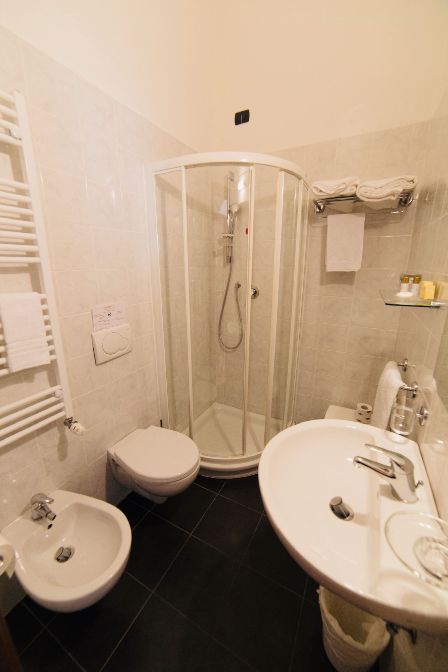 Un baño moderno con ducha envuelta en vidrio, inodoro, bidé y lavamanos.