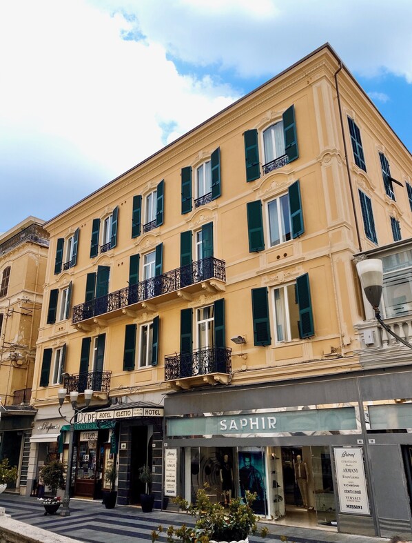 A multi-story hotel with balconies, a storefront for 'SAPHIR', and a 'Hotel Electio' sign.