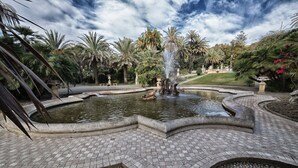 A landscaped garden with a central fountain, surrounded by palm trees and a paved walkway. - Hotel Eletto (Sanremo)