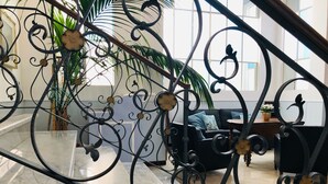 A modern interior with a marble staircase, a black sofa, and a large window allowing natural light. - Hotel Eletto (Sanremo)