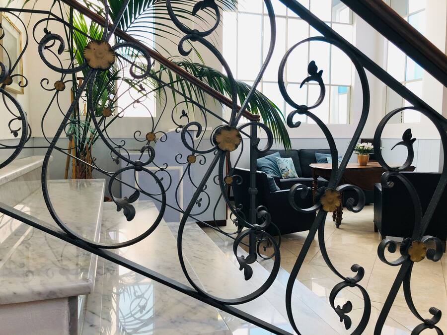 Un intérieur moderne avec un escalier en marbre, un canapé noir et une grande fenêtre laissant entrer la lumière naturelle.