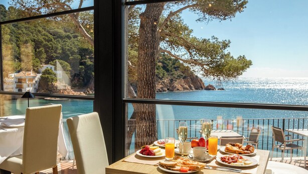 Una mesa de comedor con alimentos para el desayuno y vistas al mar.