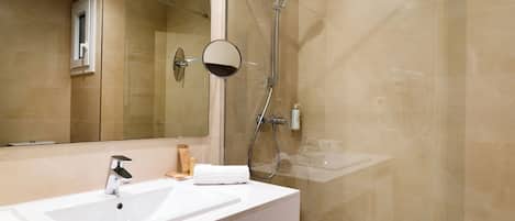 A modern bathroom with a white sink, a mirror, and a glass-enclosed shower.