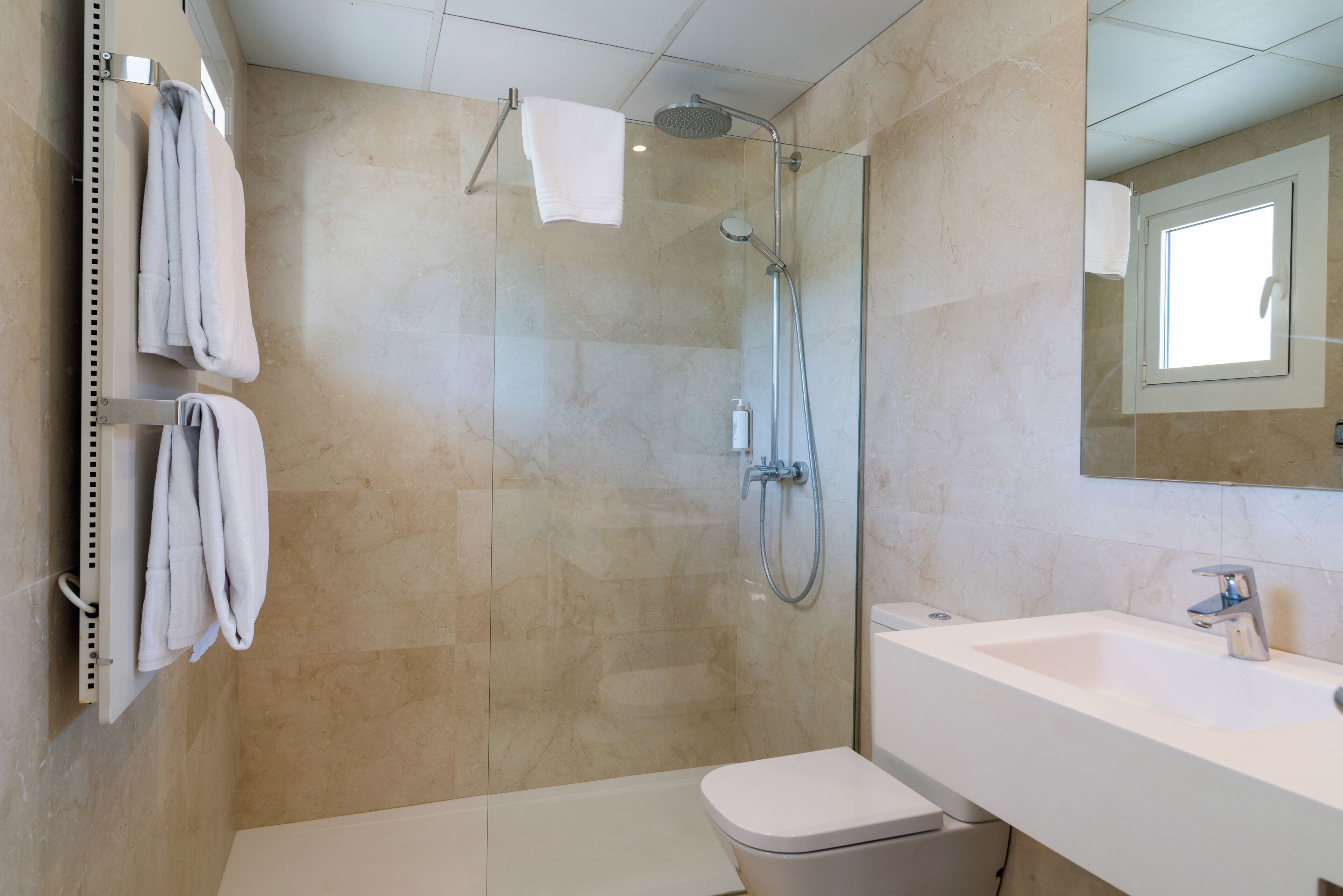 A modern bathroom with a glass-enclosed shower, a white sink, and a toilet.