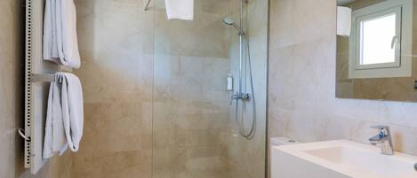A modern bathroom with a glass-enclosed shower, a white sink, and a toilet.