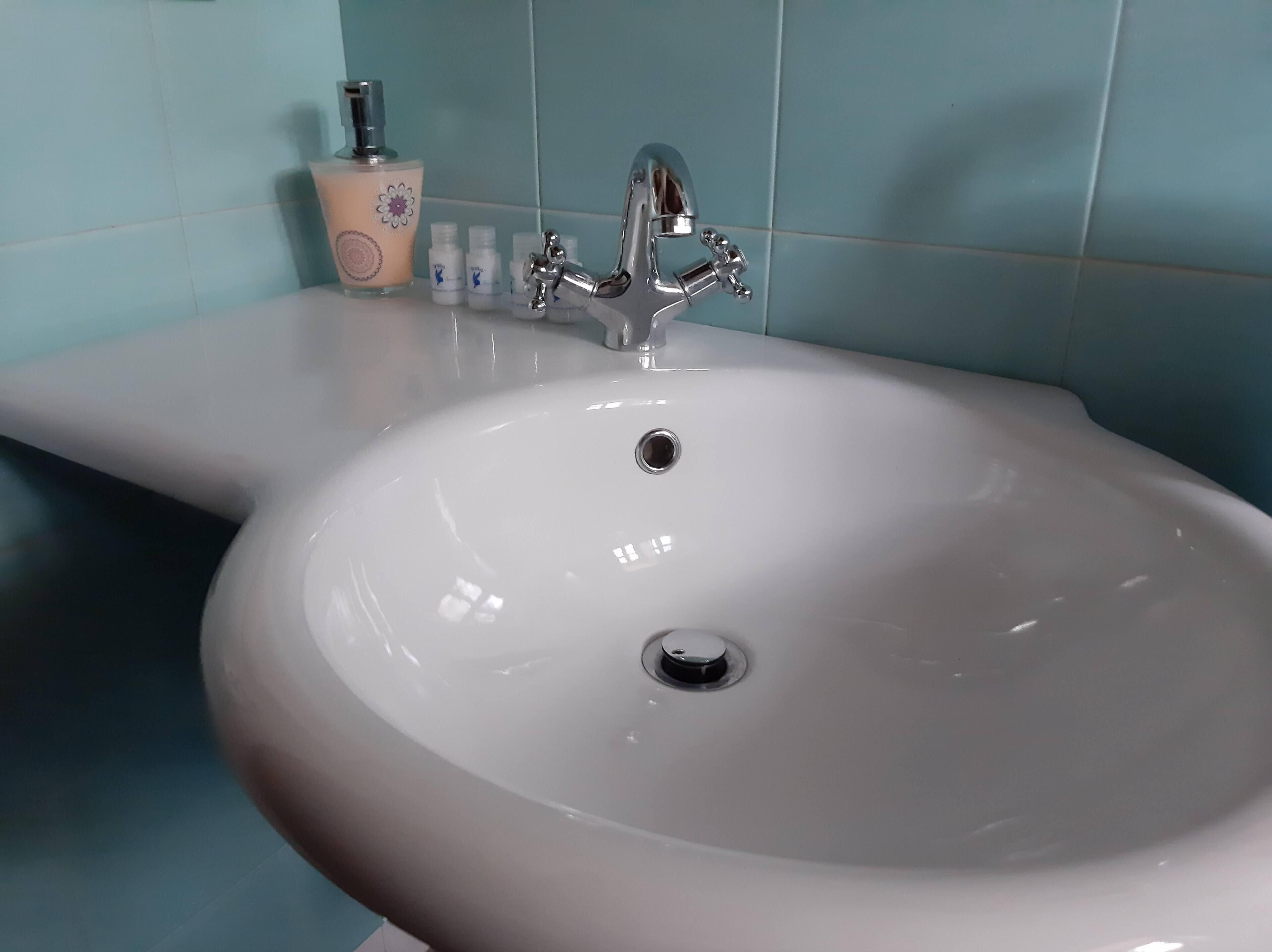 A bathroom sink with a chrome faucet and a soap dispenser.