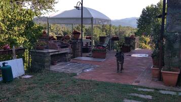 A covered patio area with a stone pathway leading to a seating area under a white canopy.